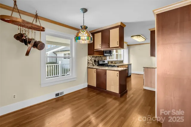 a kitchen with stainless steel appliances granite countertop a stove a sink dishwasher a refrigerator and a wooden floor