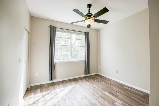 an empty room with a window and a fan