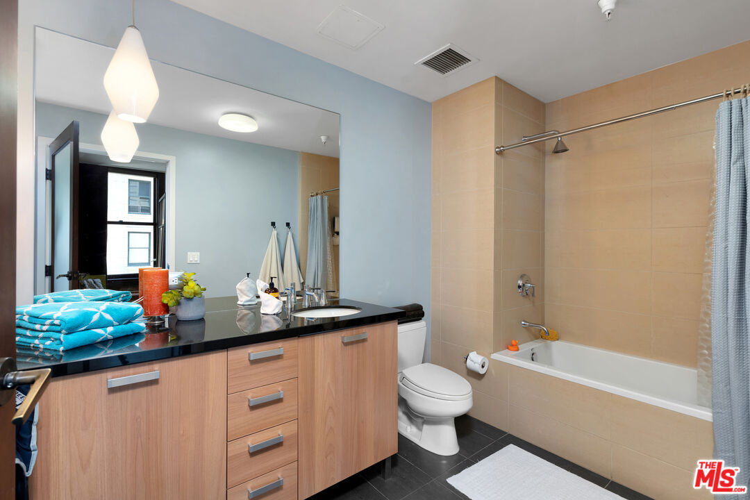 460 South Spring Street, Unit 813 Los Angeles, CA 90013 - Photo 18 of 26 a bathroom with a double vanity sink toilet mirror and bathtub