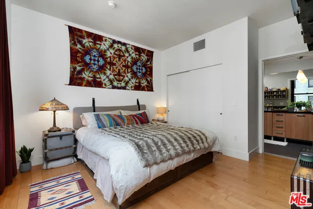 a bedroom with a bed a lamp and wooden floor
