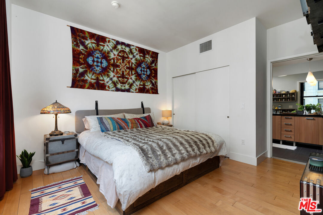 460 South Spring Street, Unit 813 Los Angeles, CA 90013 - Photo 9 of 26 a bedroom with a bed a lamp and wooden floor