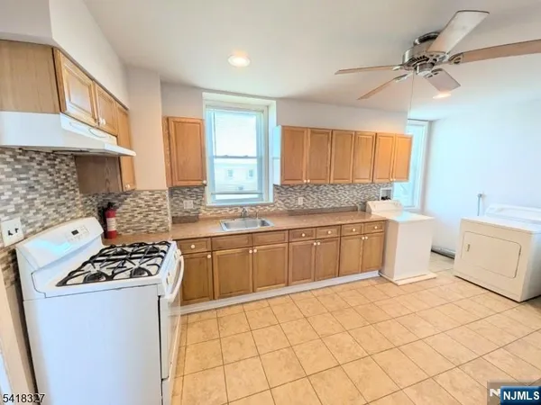 a kitchen with a stove a sink cabinets and a window