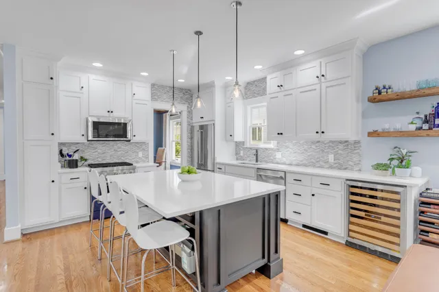 a kitchen with stainless steel appliances granite countertop a stove a sink a refrigerator and white cabinets with wooden floor