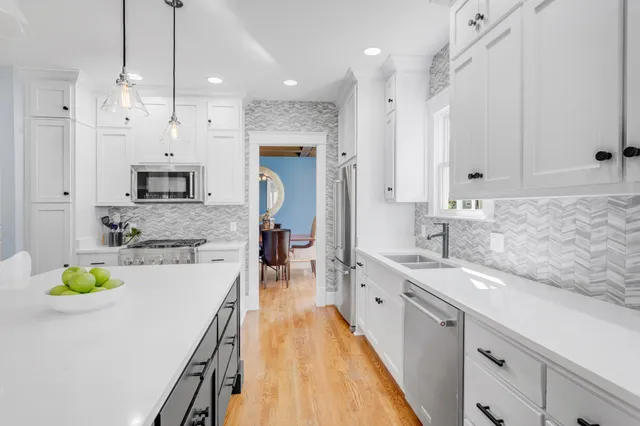 a kitchen with a stove a sink a kitchen island with chairs and wooden floor
