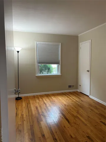 an empty room with wooden floor mirror and windows