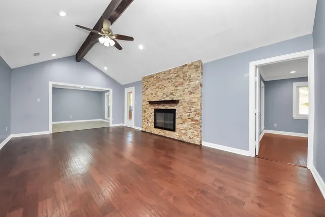 an empty room with wooden floor fireplace and windows