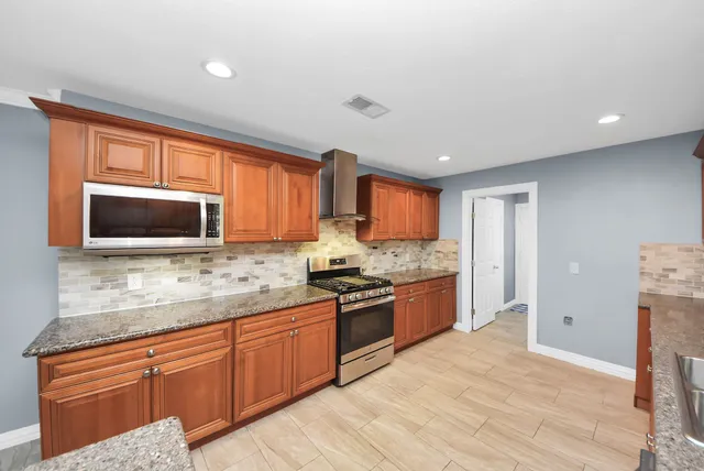 a kitchen with granite countertop a stove and a microwave