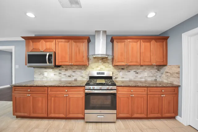 a large kitchen with stainless steel appliances granite countertop a stove a sink dishwasher and a microwave oven with cabinets