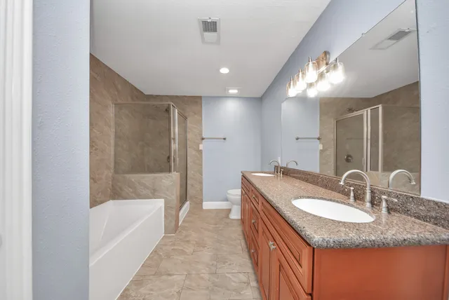a bathroom with a granite countertop sink a toilet and a large mirror