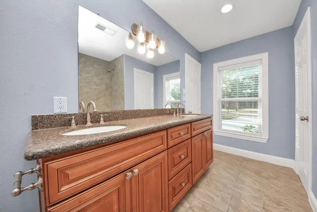 a bathroom with a granite countertop sink a bathtub a mirror a vanity and a bathtub