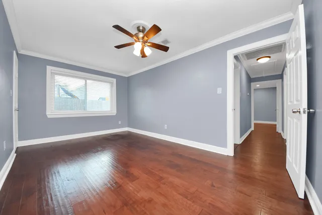an empty room with wooden floor fan and windows