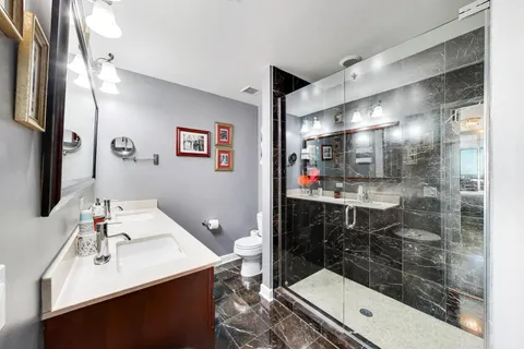 a bathroom with a sink vanity granite tub shower and a mirror