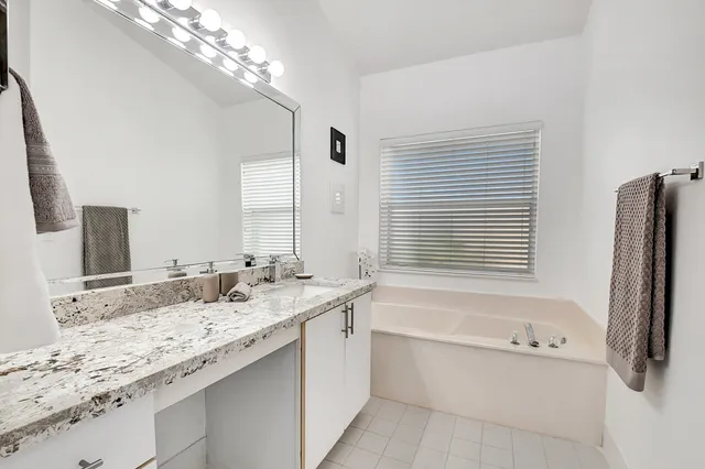 a bathroom with a granite countertop sink a large mirror and a bathtub with shower