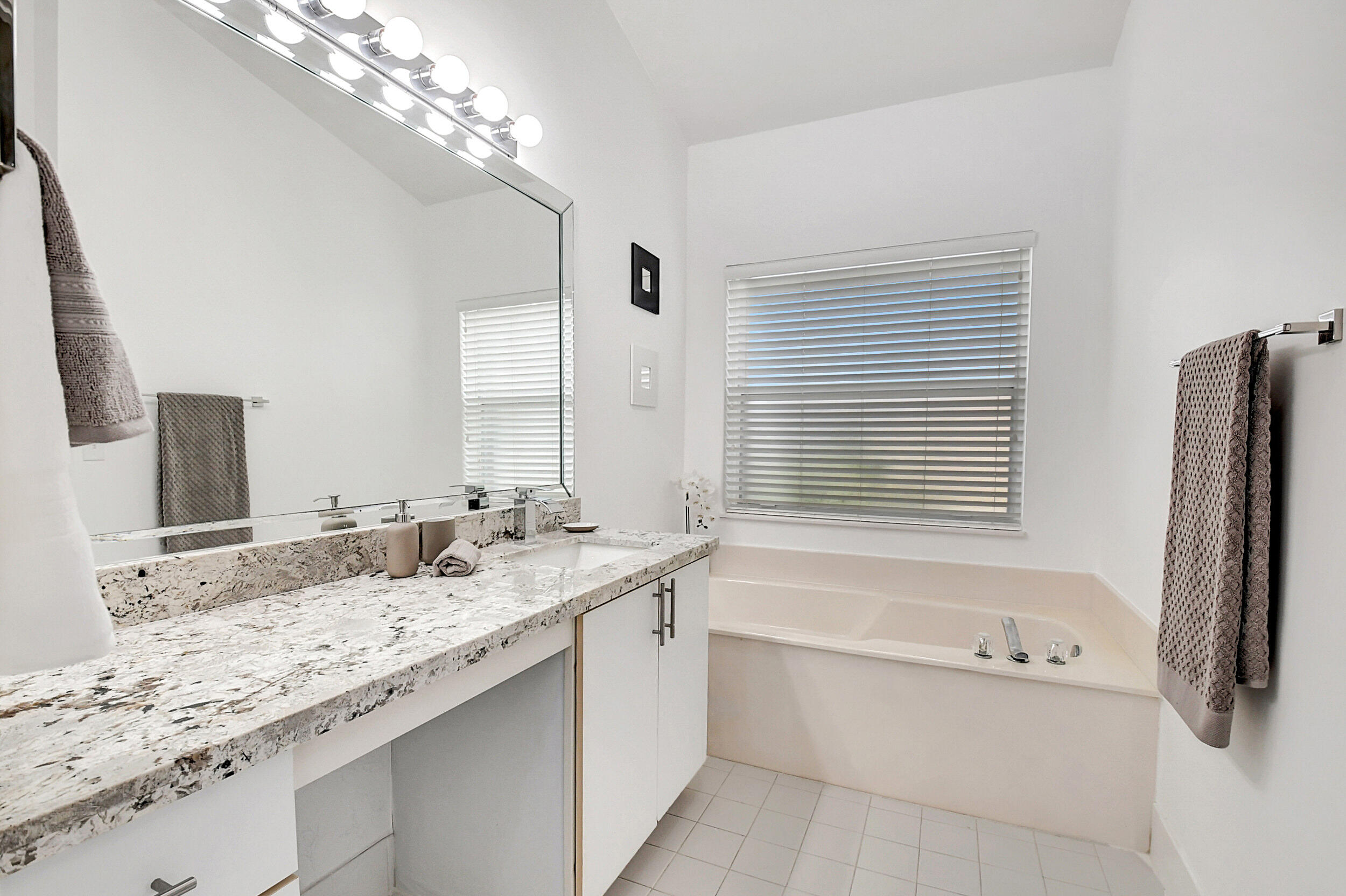 6340 Long Key Lane Boynton Beach, FL 33472 - Photo 12 of 29 a bathroom with a granite countertop sink a large mirror and a bathtub with shower