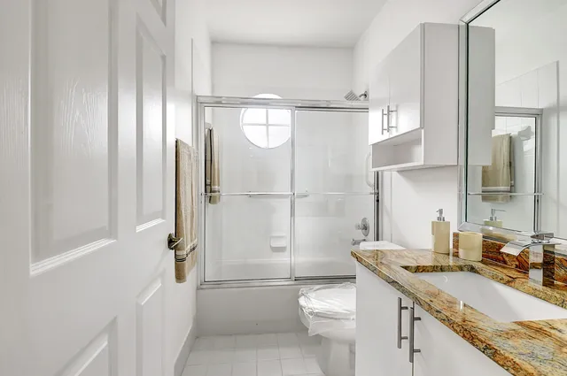 a bathroom with a granite countertop sink toilet and shower