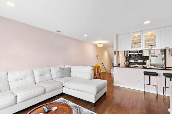 a living room with stainless steel appliances kitchen island granite countertop furniture and a wooden floor