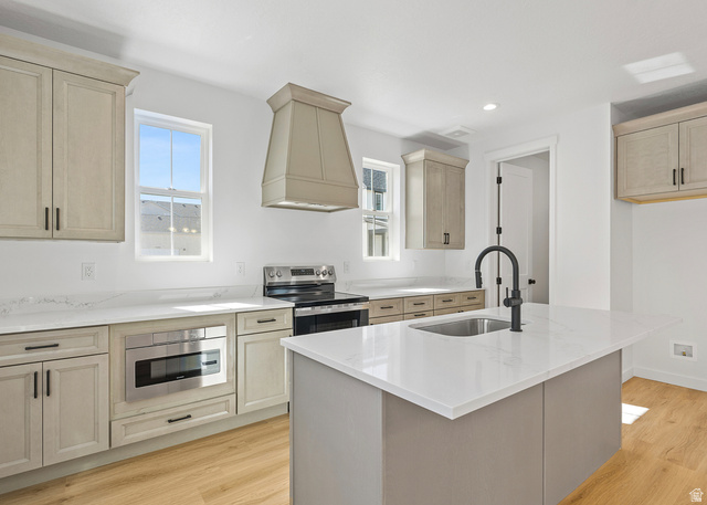 11214 South Easy Bee Road, Unit 270 South Jordan, UT 84009 - Photo 6 of 31 Modern kitchen featuring light wood-finish cabinetry, white countertops, an integrated stainless steel microwave, a black range, and a kitchen island with a matte black faucet