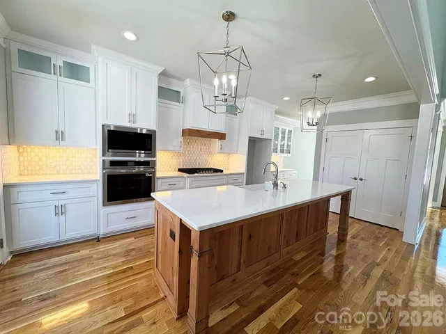 a view of a kitchen with a sink a kitchen island a stove and a chandelier