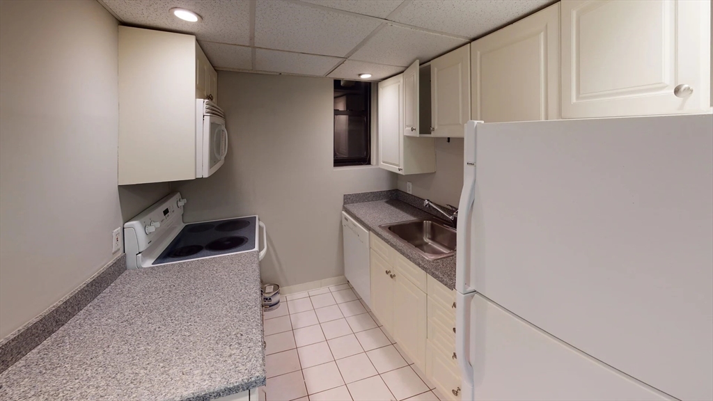 a kitchen with granite countertop a stove a sink and a refrigerator