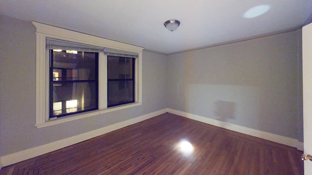 466 Commonwealth Avenue, Unit 406 Boston, MA 02215 - Photo 3 of 8 a view of an empty room with wooden floor and a window