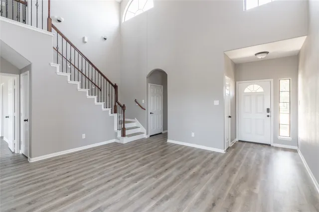 a view of an empty room with wooden floor and stairs