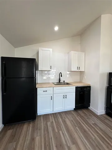 a kitchen with a refrigerator and white cabinets