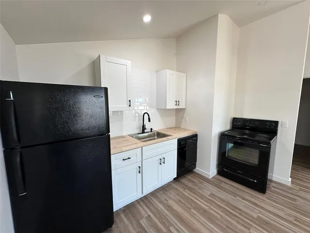 an empty room with wooden floor fireplace and windows