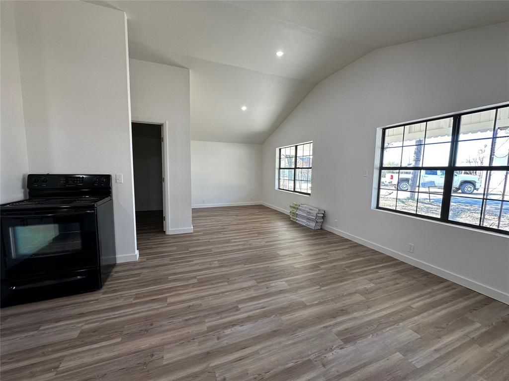 102 North Pinto Street Comanche, TX 76442 - Photo 19 of 23 an empty room with wooden floor fireplace and windows