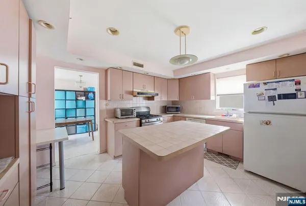 a kitchen with a refrigerator a stove top oven a sink dishwasher and white cabinets next to a window