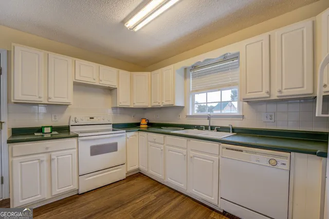 a kitchen with granite countertop a table chairs stove a refrigerator and dining table with wooden floor