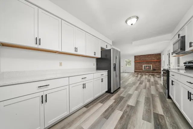 a kitchen with granite countertop white cabinets and stainless steel appliances