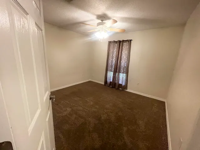 an empty room with windows and fan