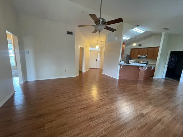 an empty room with kitchen view and wooden floor