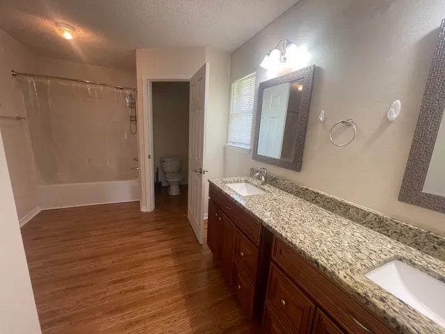 a bathroom with a granite countertop double vanity sink and mirror