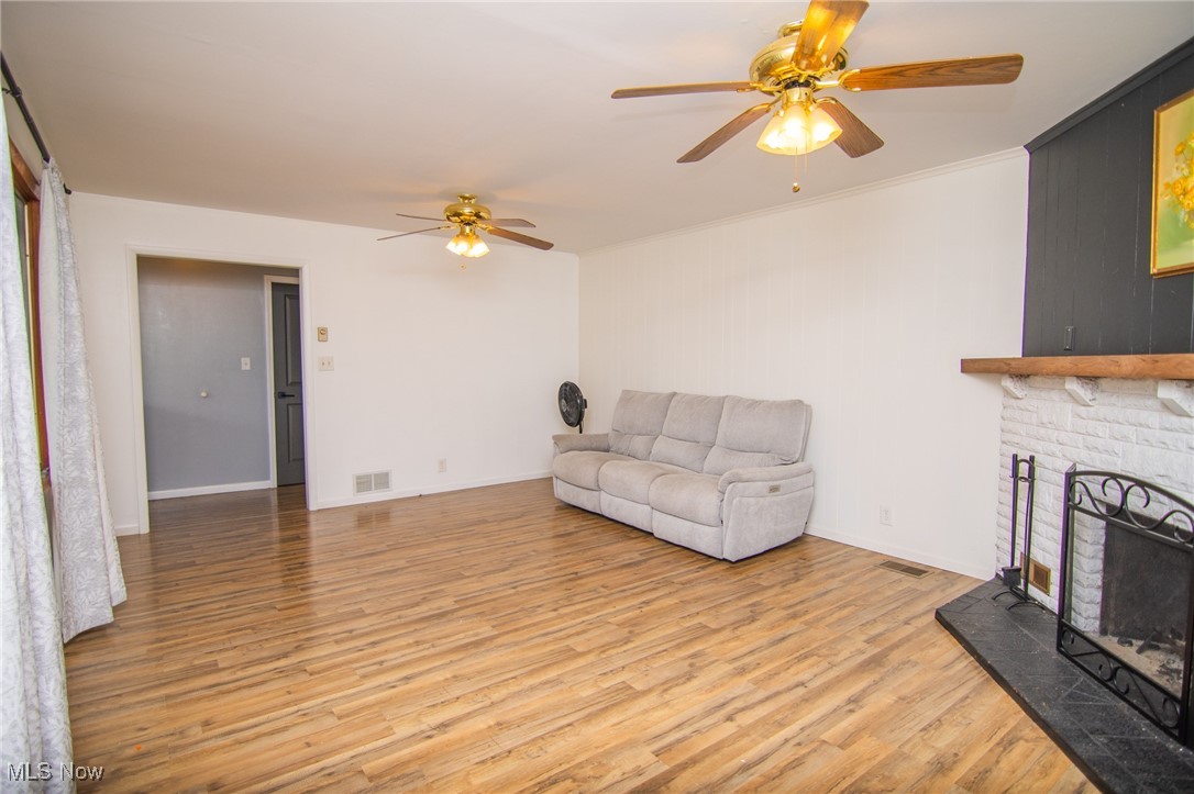 70973 Morristown Flushing Road Flushing, OH 43977 - Photo 43 of 44 Living room featuring light wood-type flooring, a fireplace with raised hearth, ceiling fan, and ornamental molding