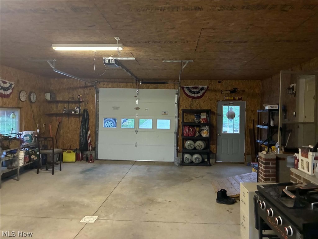 4601 Bessemer Road Nelsonville, OH 45764 - Photo 12 of 25 Concrete flooring, wood panel walls, overhead fluorescent lighting, roll-up garage door, side entry door with window