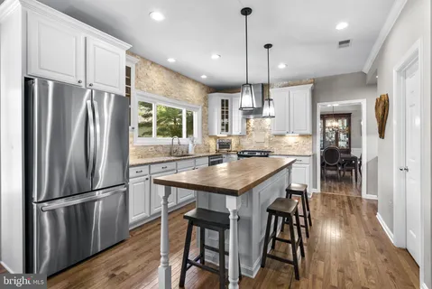 a kitchen with granite countertop a sink a center island stainless steel appliances and cabinets
