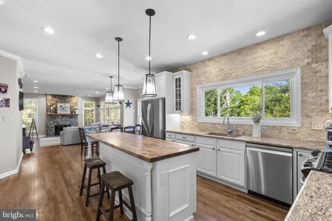 a kitchen with granite countertop kitchen island stainless steel appliances a stove and wooden floor