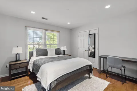 a spacious bedroom with a bed a table and chair with wooden floor
