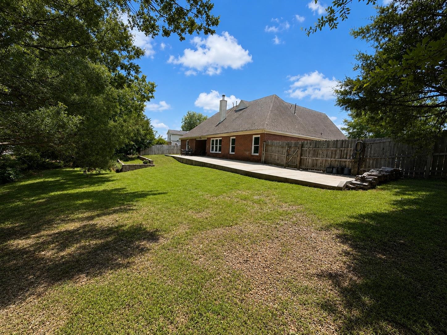 326 South Sanga Road Cordova, TN 38018 - Photo 32 of 32 Expansive backyard featuring a large concrete patio, mature trees, and a wooden privacy fence