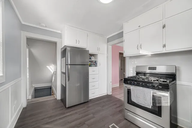 a kitchen with a refrigerator a stove and white cabinets