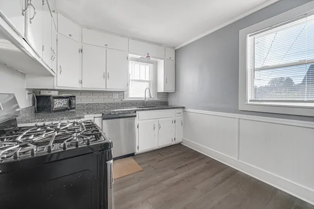 a kitchen with white cabinets and window