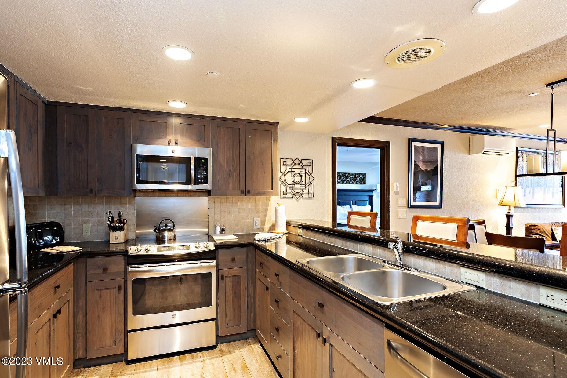 210 Offerson Road, Unit 115 WEEK 33 Beaver Creek, CO 81620 - Photo 7 of 23 a kitchen with granite countertop a sink and a stove top oven