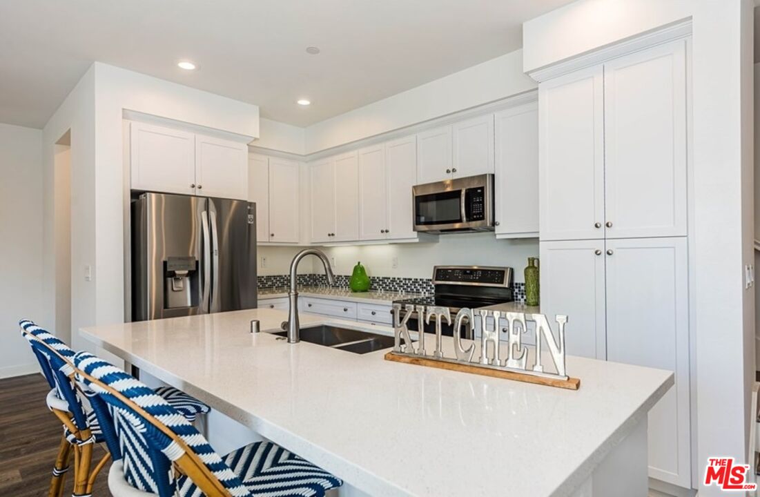 5304 Harvard Way Cypress, CA 90630 - Photo 5 of 29 a kitchen with stainless steel appliances granite countertop a refrigerator a stove a sink a dining table and chairs