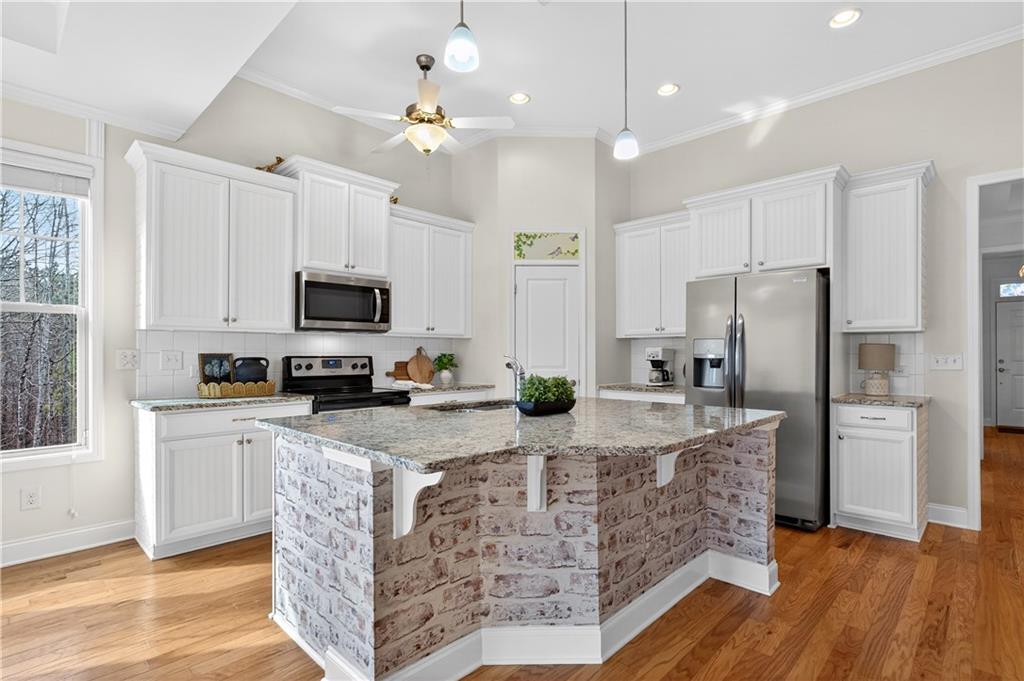 310 Pepperwood Way Canton, GA 30114 - Photo 11 of 54 a kitchen with stainless steel appliances kitchen island granite countertop a refrigerator a stove top oven a sink and dishwasher with wooden floor