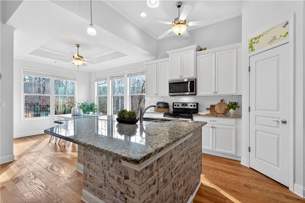 310 Pepperwood Way Canton, GA 30114 - Photo 10 of 54 a kitchen with stainless steel appliances granite countertop a stove top oven a refrigerator a sink dishwasher a dining table and chairs with wooden floor