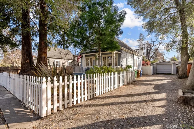 a view of a white house with wooden fence and a large tree