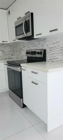 a kitchen with granite countertop cabinets stove and microwave