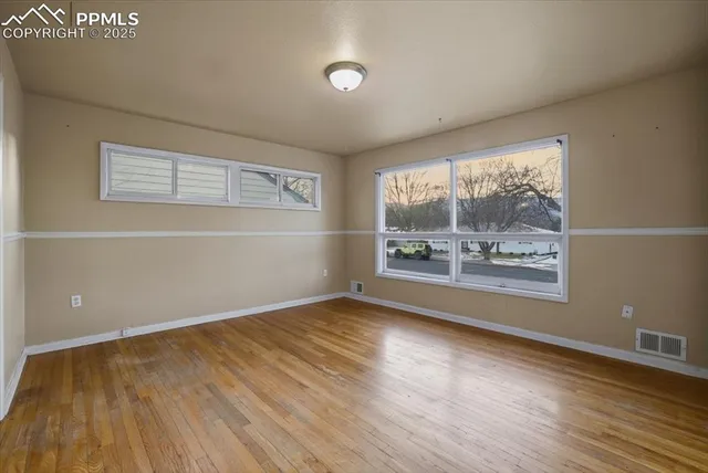 a view of an empty room with a window and wooden floor