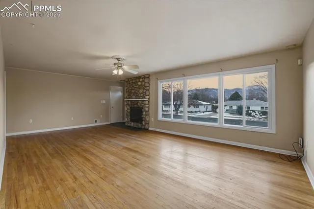 a view of an empty room with a window and wooden floor